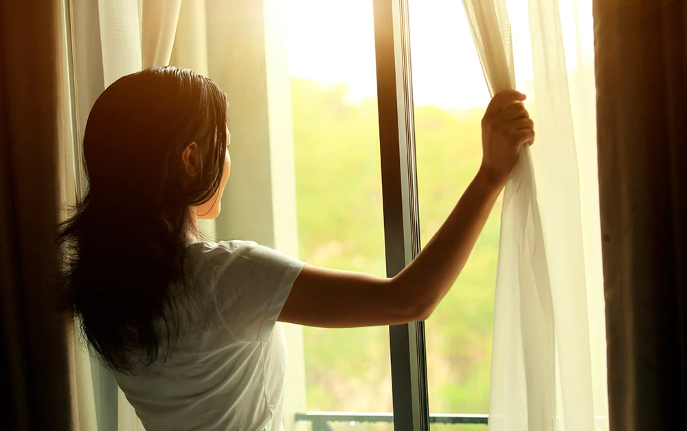 Mulher abrindo cortina